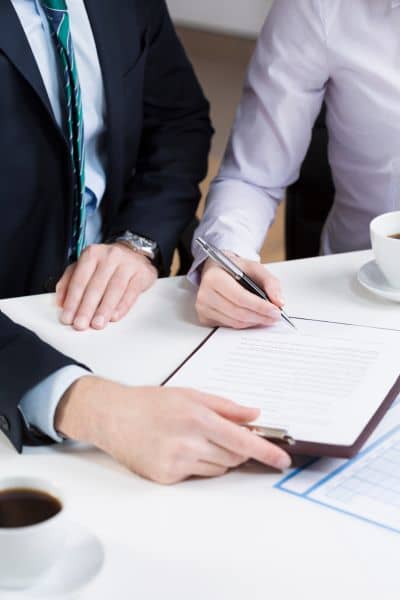 Buyer and surveyor reviewing and signing documents during the due diligence phase for ordering an ALTA survey.
