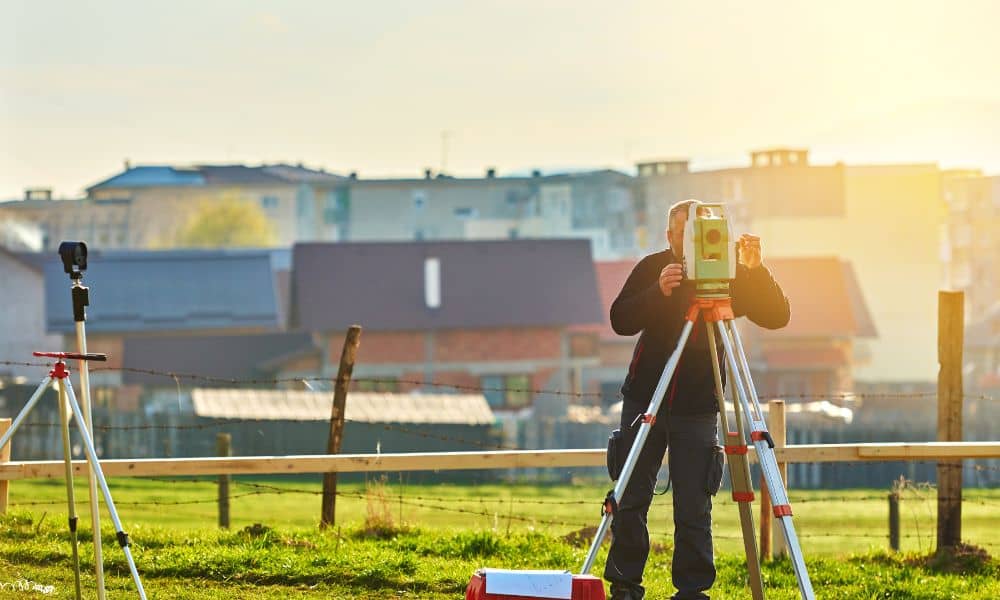 Licensed land surveyor in San Diego performing a boundary survey on a residential property with professional equipment.
