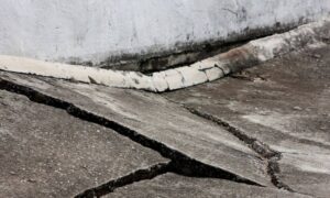 Cracked and uneven concrete pavement caused by land subsidence, highlighting the importance of land surveying to detect and manage ground sinking.