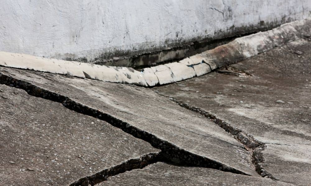 Cracked and uneven concrete pavement caused by land subsidence, highlighting the importance of land surveying to detect and manage ground sinking.