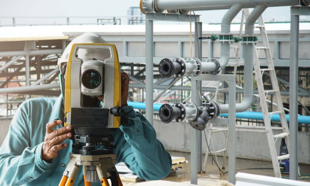 Surveyor using a total station during an ALTA Land Title Survey at an active construction site to ensure accuracy and safety
