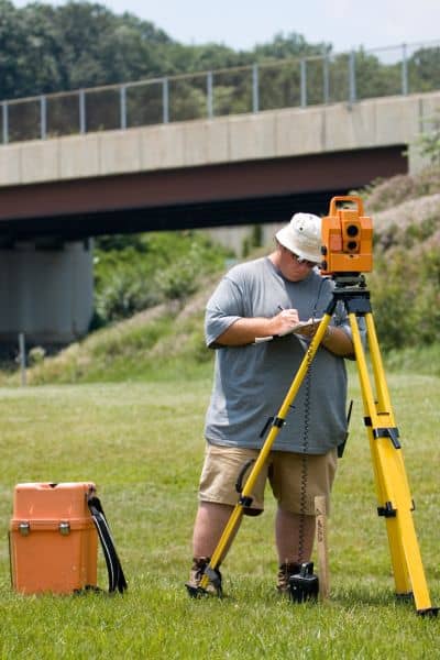 Licensed land surveyor conducting field measurements for a loan closing survey to help verify property data during the NFIP freeze
