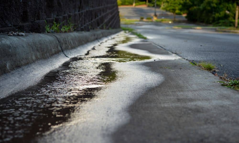 Stormwater runoff along a sloped curb showing how rain highlights the need for a topographic survey