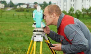 Land surveyor measuring property elevation for a FEMA Elevation Certificate review