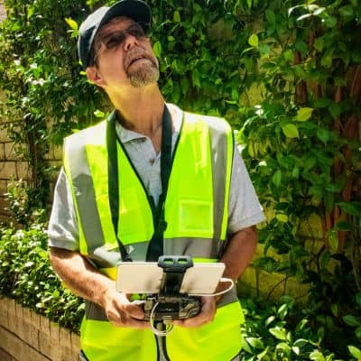 Licensed surveyor operating a drone controller during a uav survey to ensure compliant data collection and consistent results