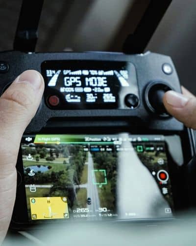 Drone surveyor operating a controller while viewing live aerial mapping data from a drone